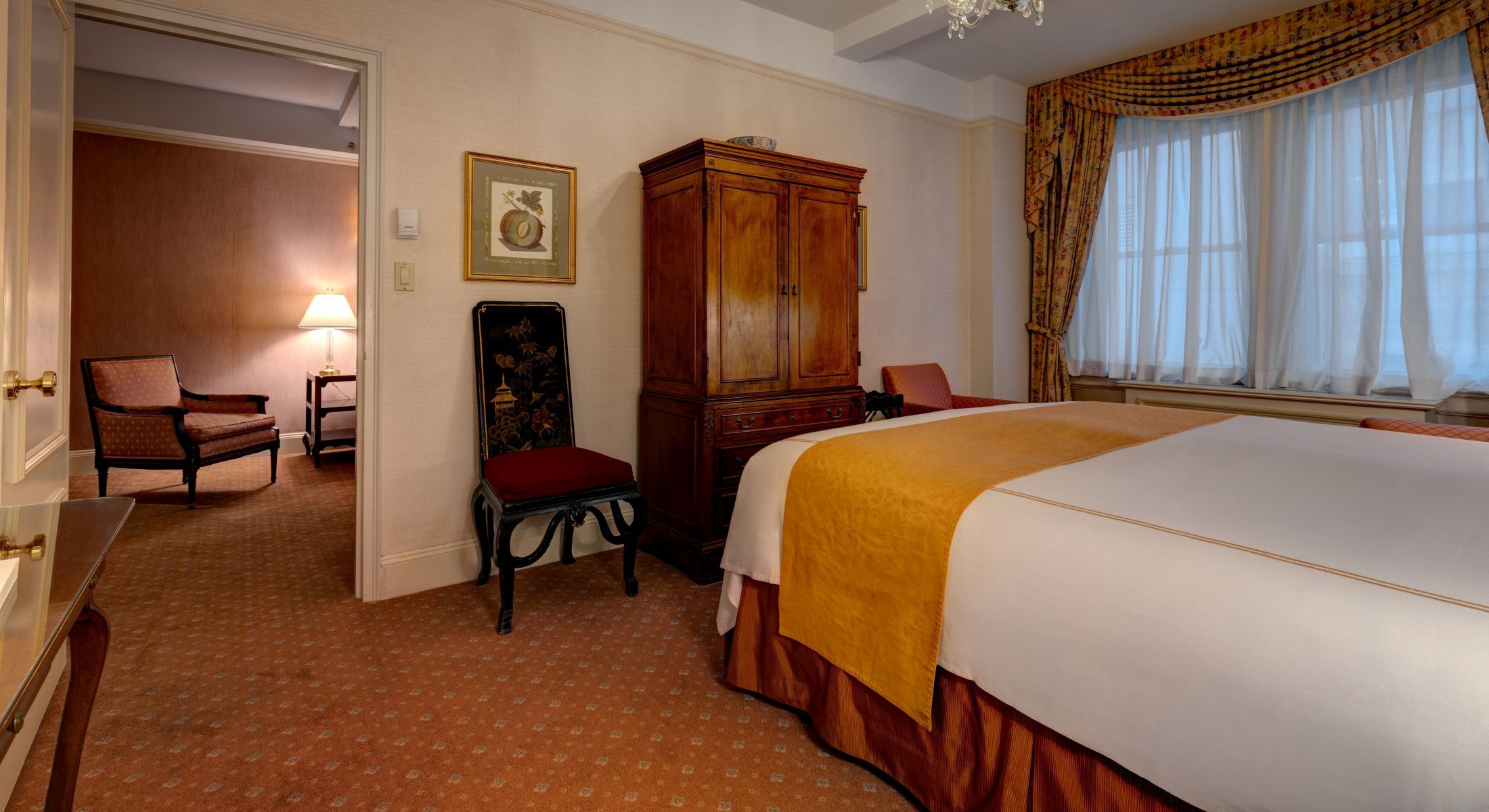 Bedroom of the King Suite at the Hotel Elysee with king bed and armoire.